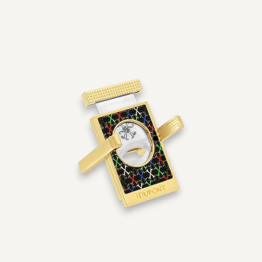 Arcadia Cigars S.T. Dupont gold cigar cutter with black face, red, white, green, blue X pattern, and textured grip.