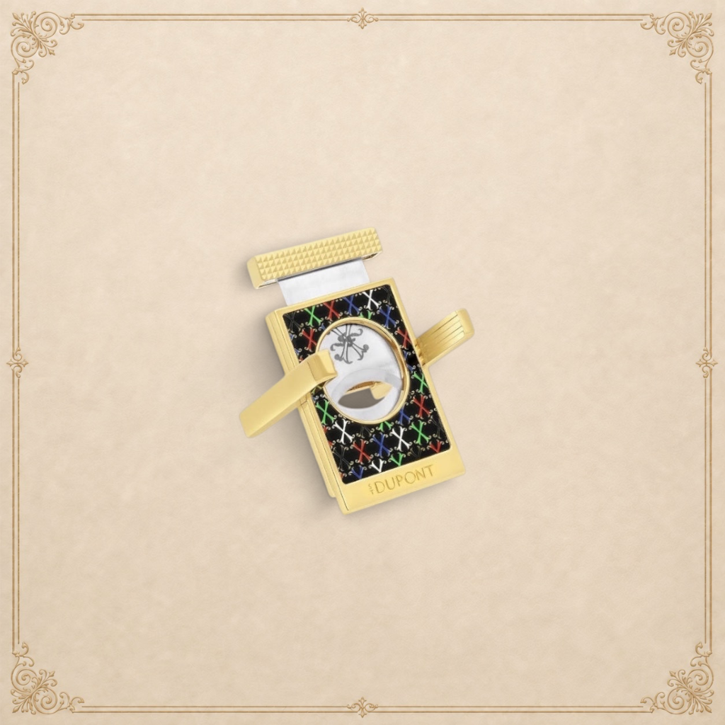 Arcadia Cigars S.T. Dupont gold cigar cutter with black face, red, white, green, blue X pattern, and textured grip.